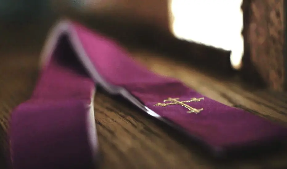 Purple stole with gold cross on wood.