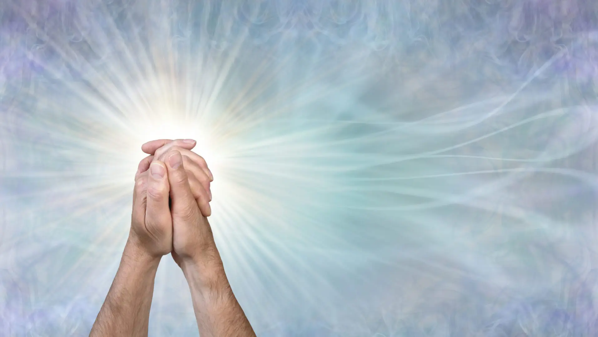 male hands in clasped prayer position against a wispy flowing blue background with copy space for message or religious prayer