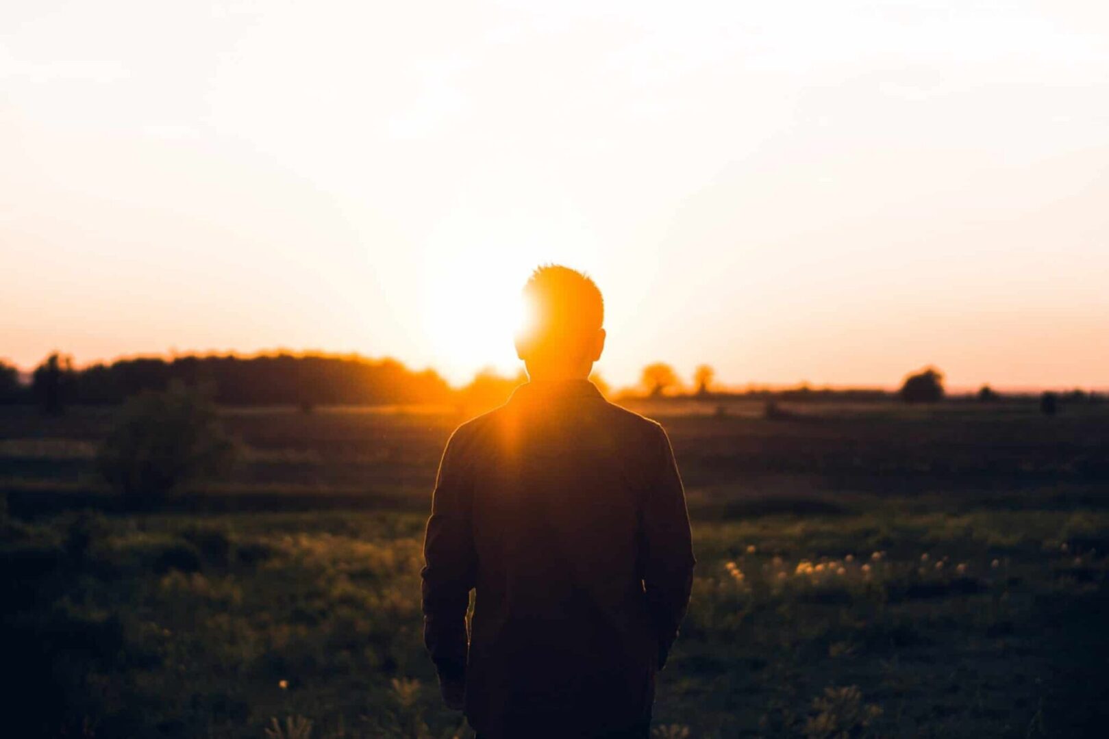 Silhouette of a man facing sunset.