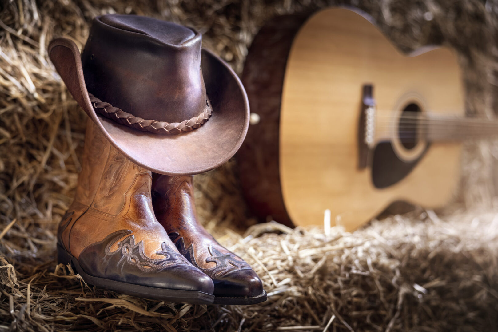 Country music festival live concert or rodeo with cowboy hat guitar and boots in barn background
