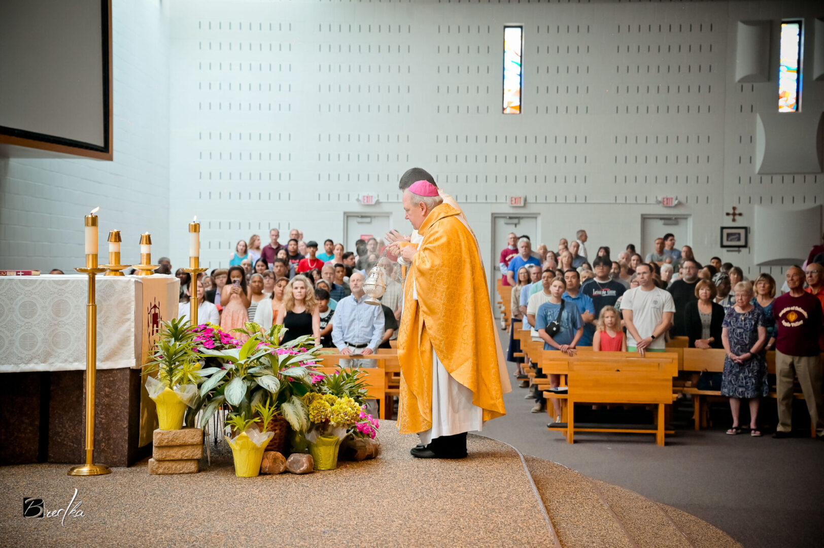 Bishop in yellow robe censing congregation.
