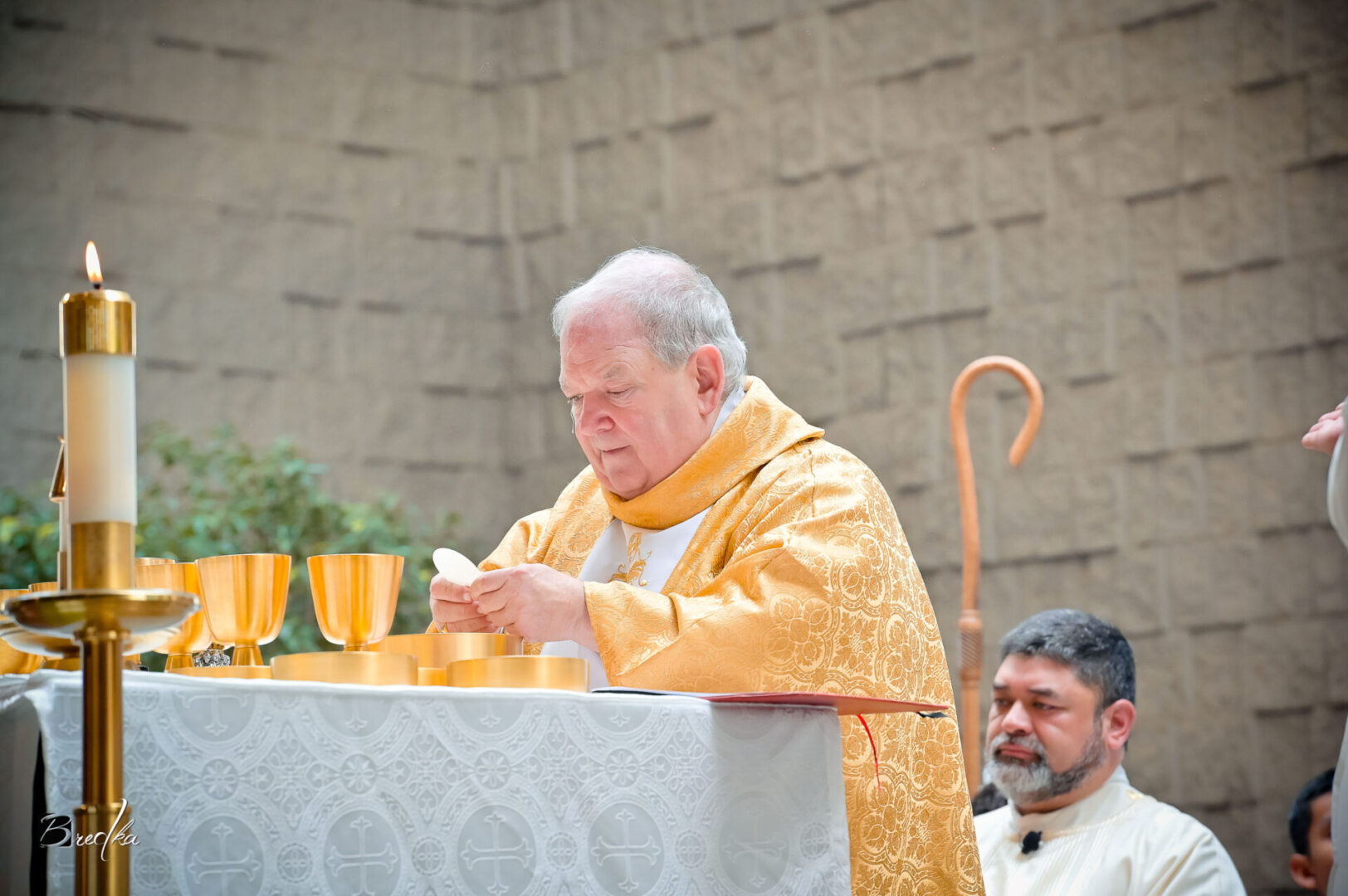 Priest holding communion wafer at altar.