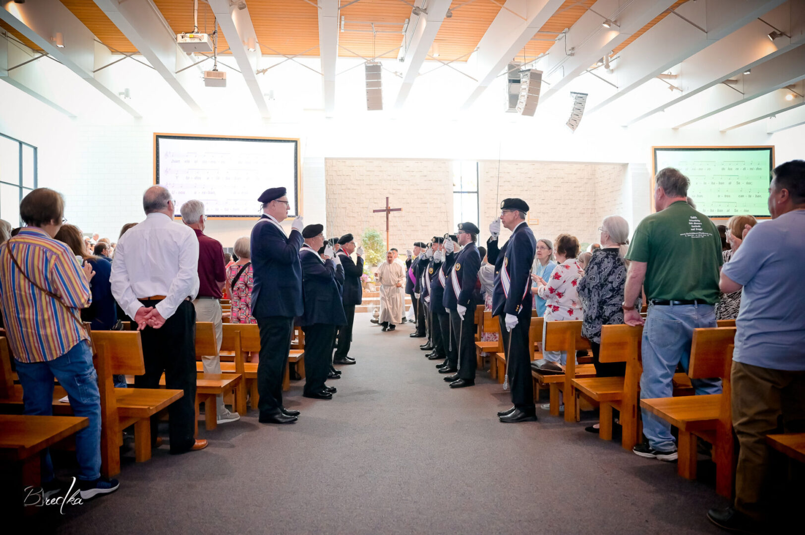 Men in uniform stand in church pews.