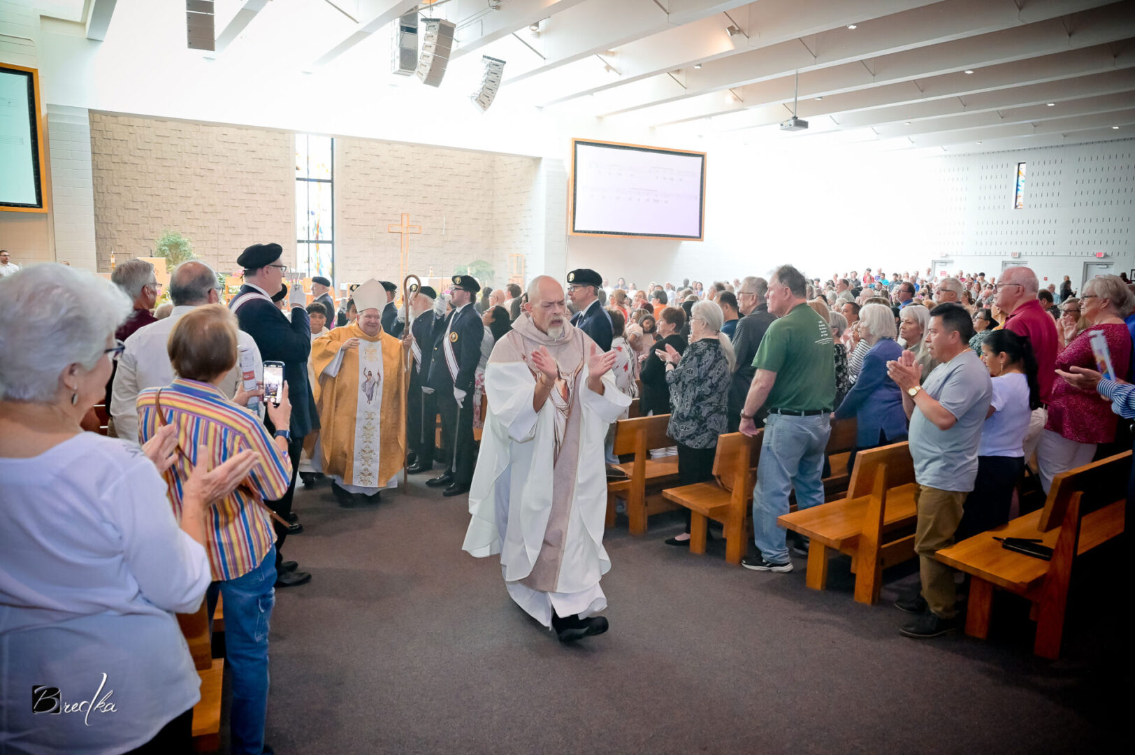 Man in white robe walks in church service.
