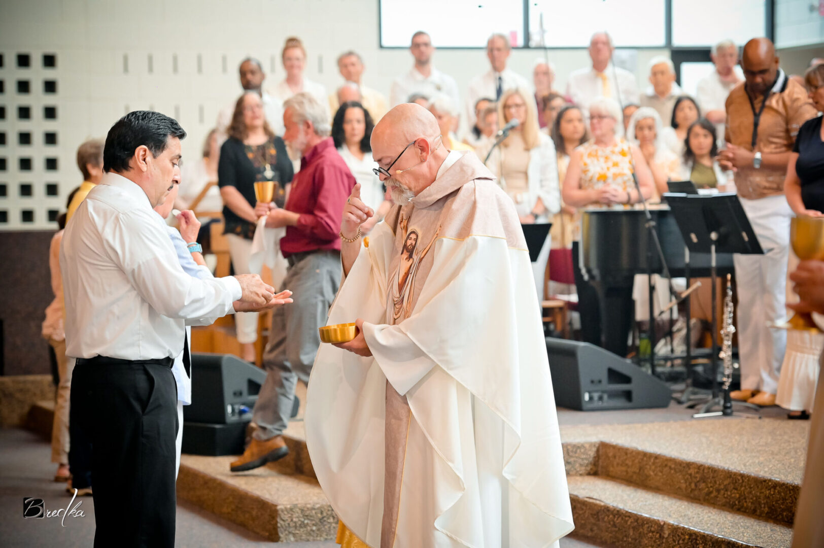 Man receiving communion from priest in church.