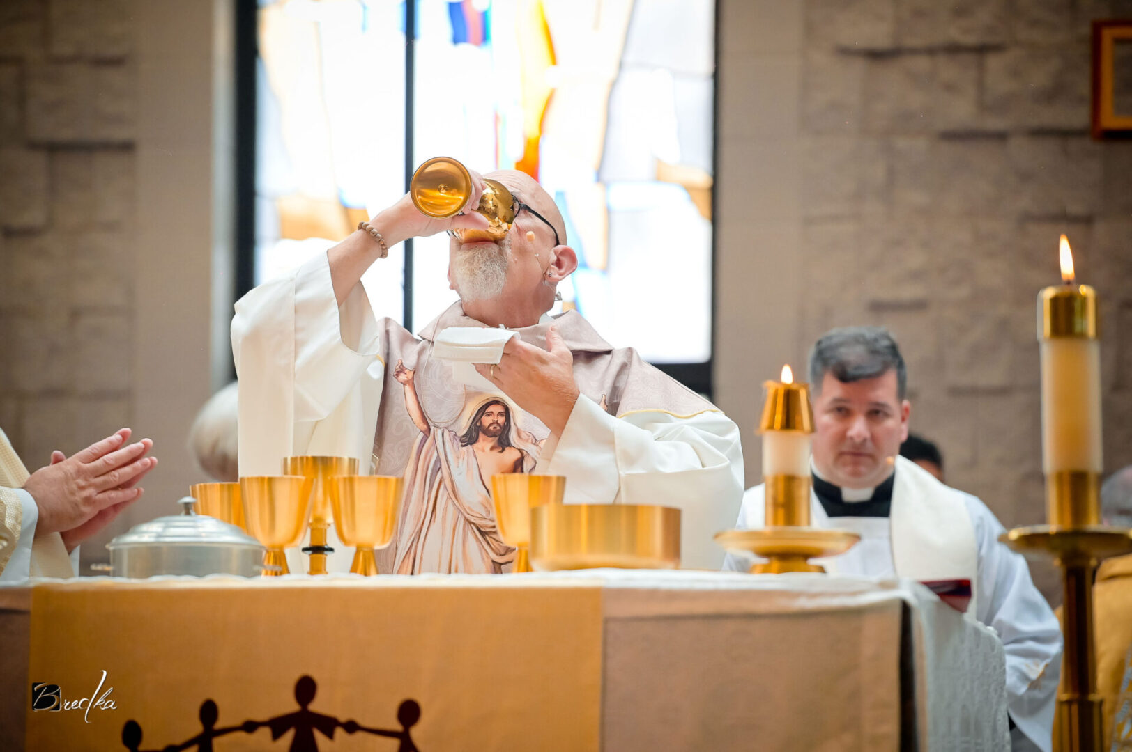 Priest drinking wine during communion service.
