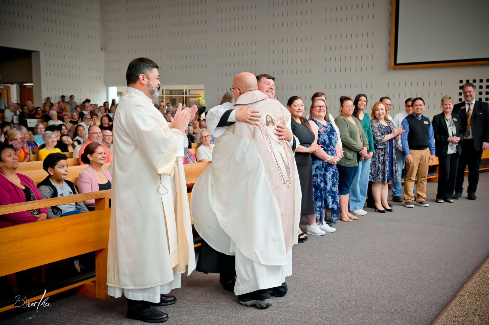 Two priests embrace in church ceremony.