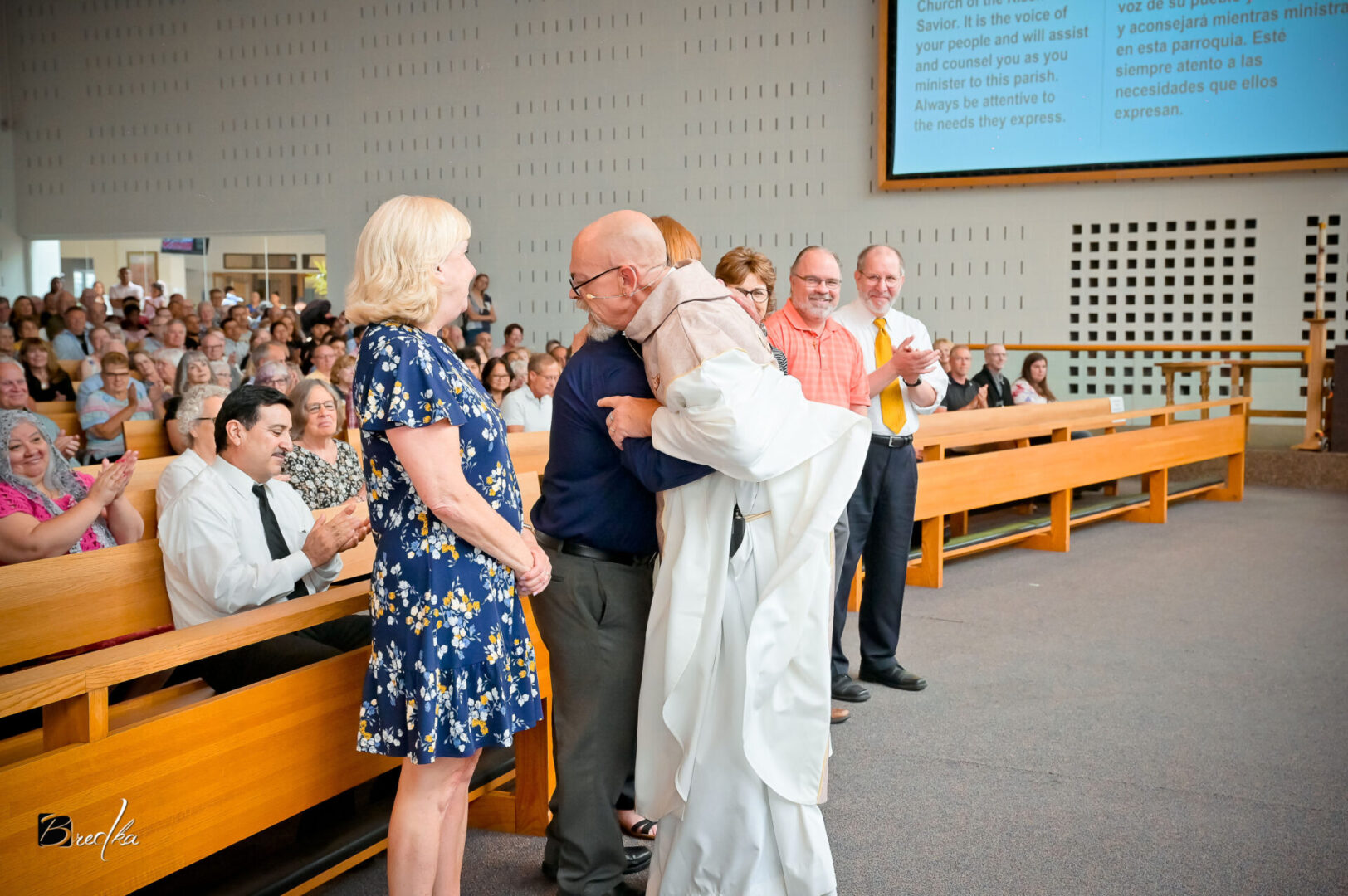 A man embraces a priest in a church.