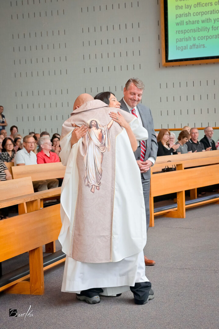 Man in white robe being hugged by a woman.