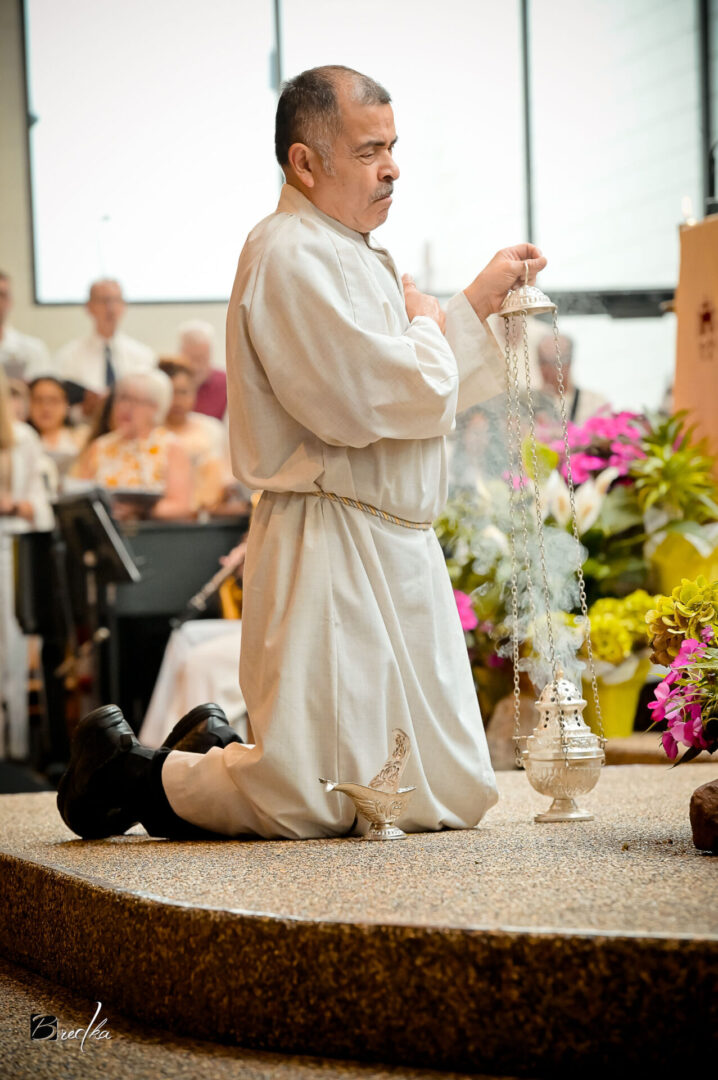 Man kneeling with a censer and incense.